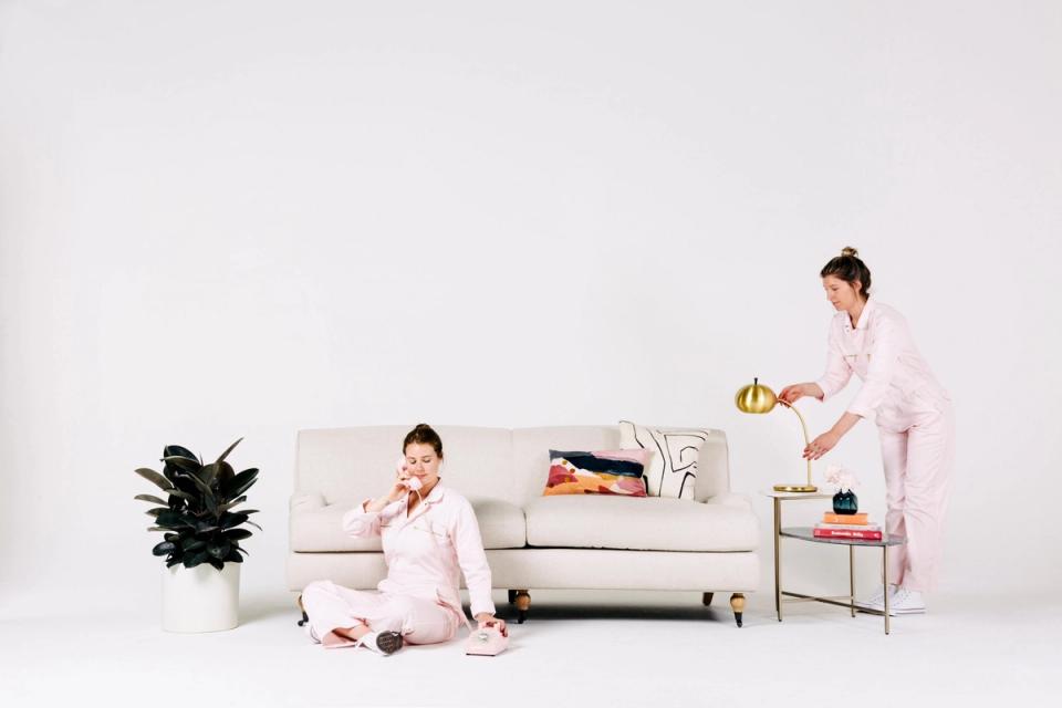 Minimalist living room with cream sofa, potted plant, and organized storage styling modern, clean aesthetic