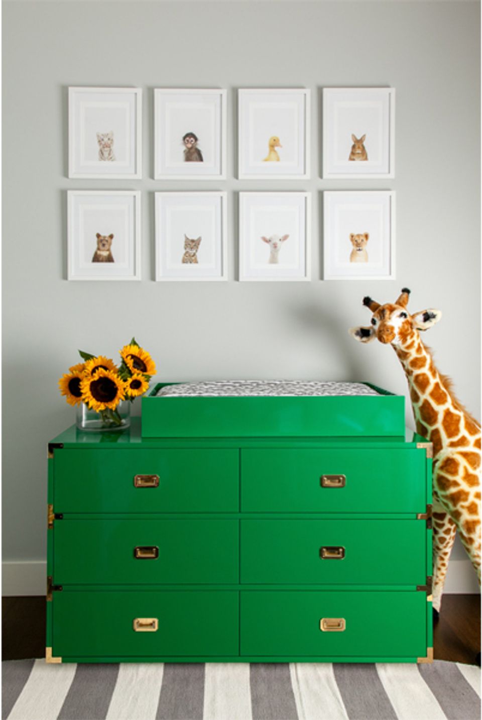 Playful nursery with emerald campaign dresser, animal portrait gallery wall, and safari-inspired decor