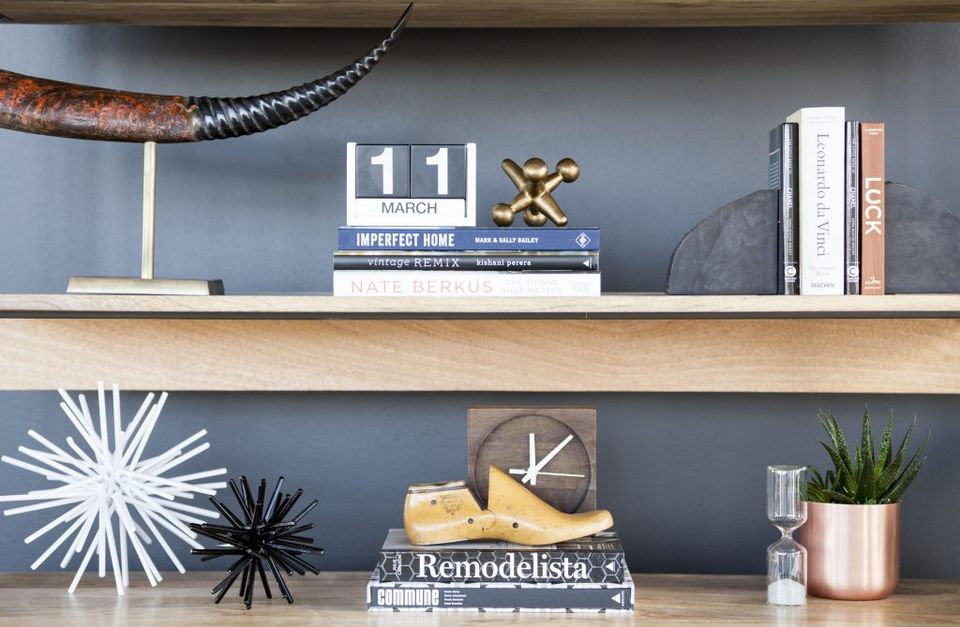 Modern industrial shelving with slate-blue backdrop, mixed metals, and curated decor in a minimalist, organized aesthetic.
