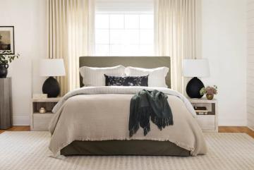 Modern coastal bedroom with neutral beige and charcoal palette, layered pillows, and floor-to-ceiling cream curtains creating serene elegance
