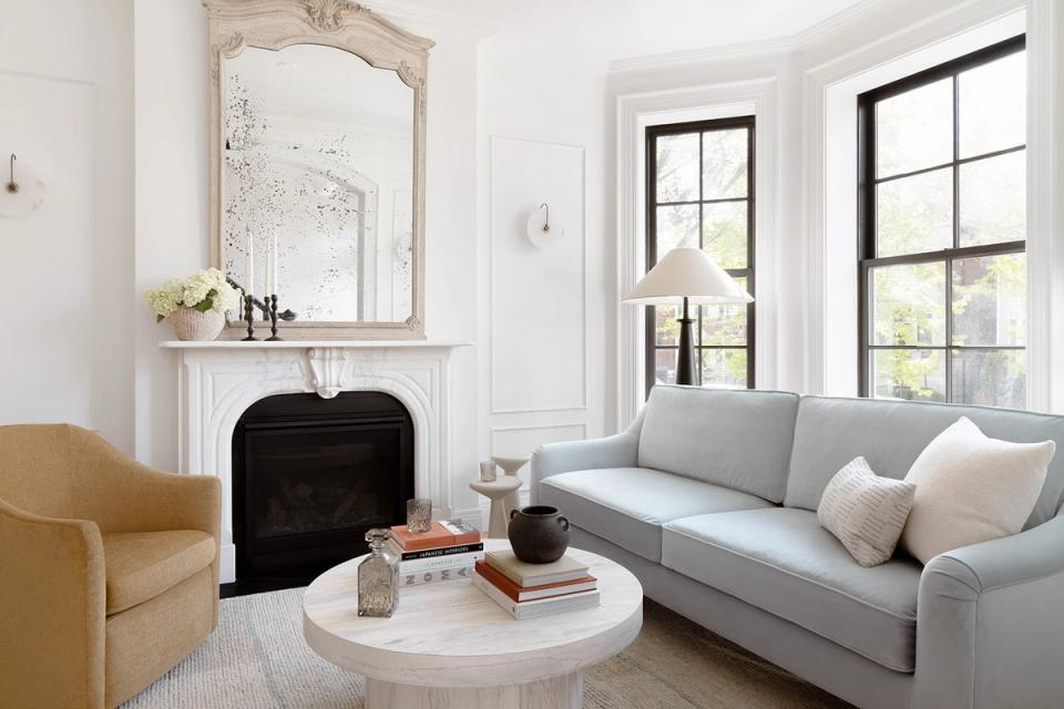 Transitional living room with soft gray sofa, mustard accent chair, and marble fireplace under ornate mirror