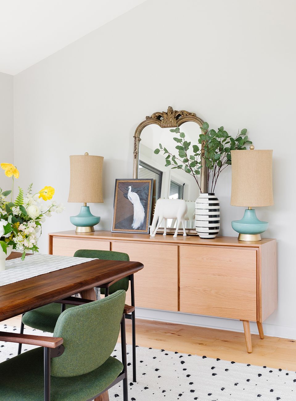 Contemporary workspace with natural wood dresser, blue lamps, and botanical accents.