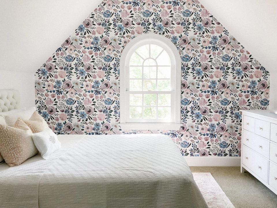 Cottage bedroom with floral accent wallpaper in soft pink and blue tones creating a romantic, whimsical atmosphere.