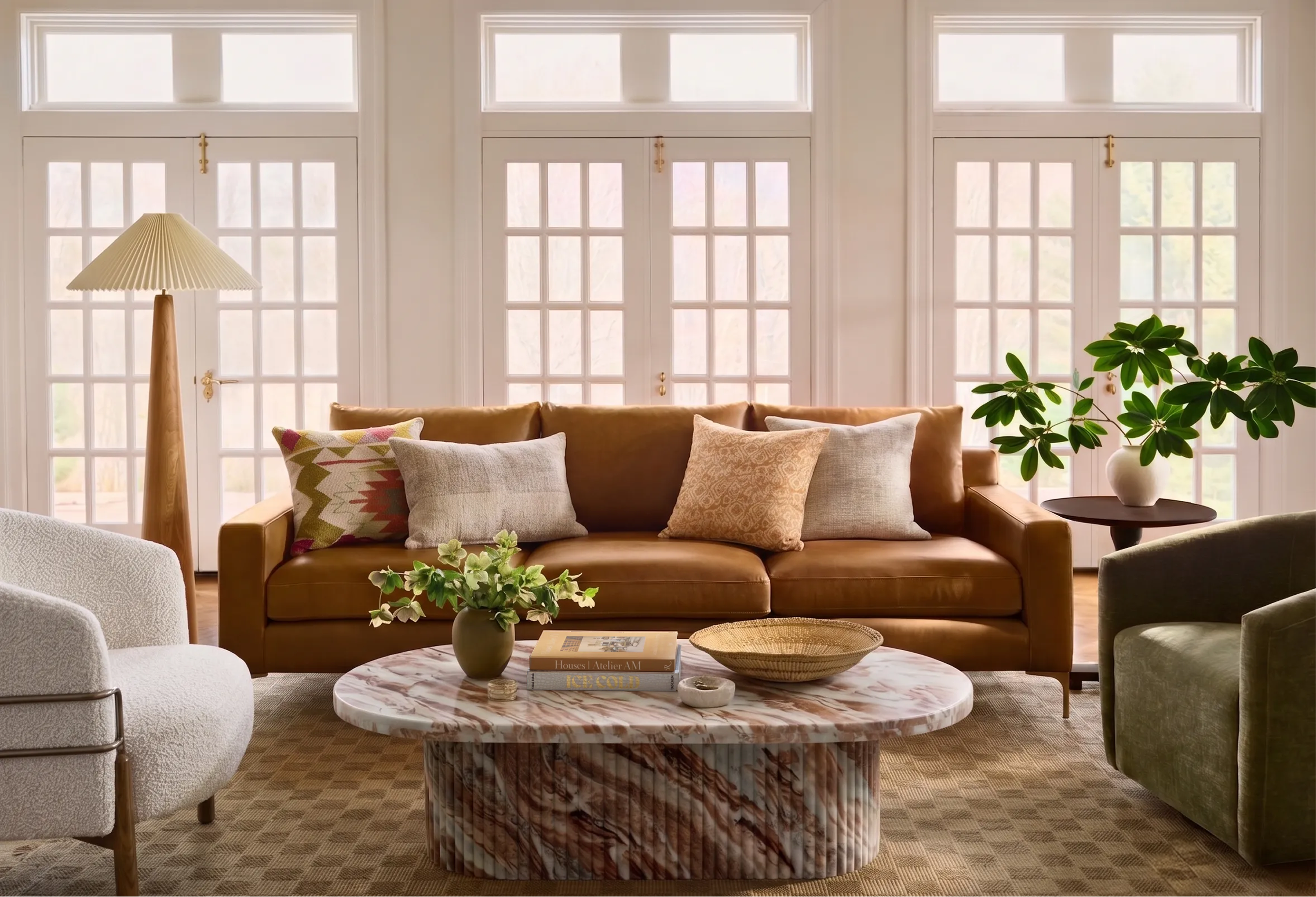 Living room with brown leather sofa, green velvet chair, marble coffee table.
