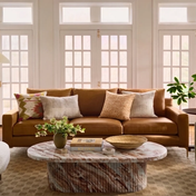 Living room with brown leather sofa, green velvet chair, marble coffee table.