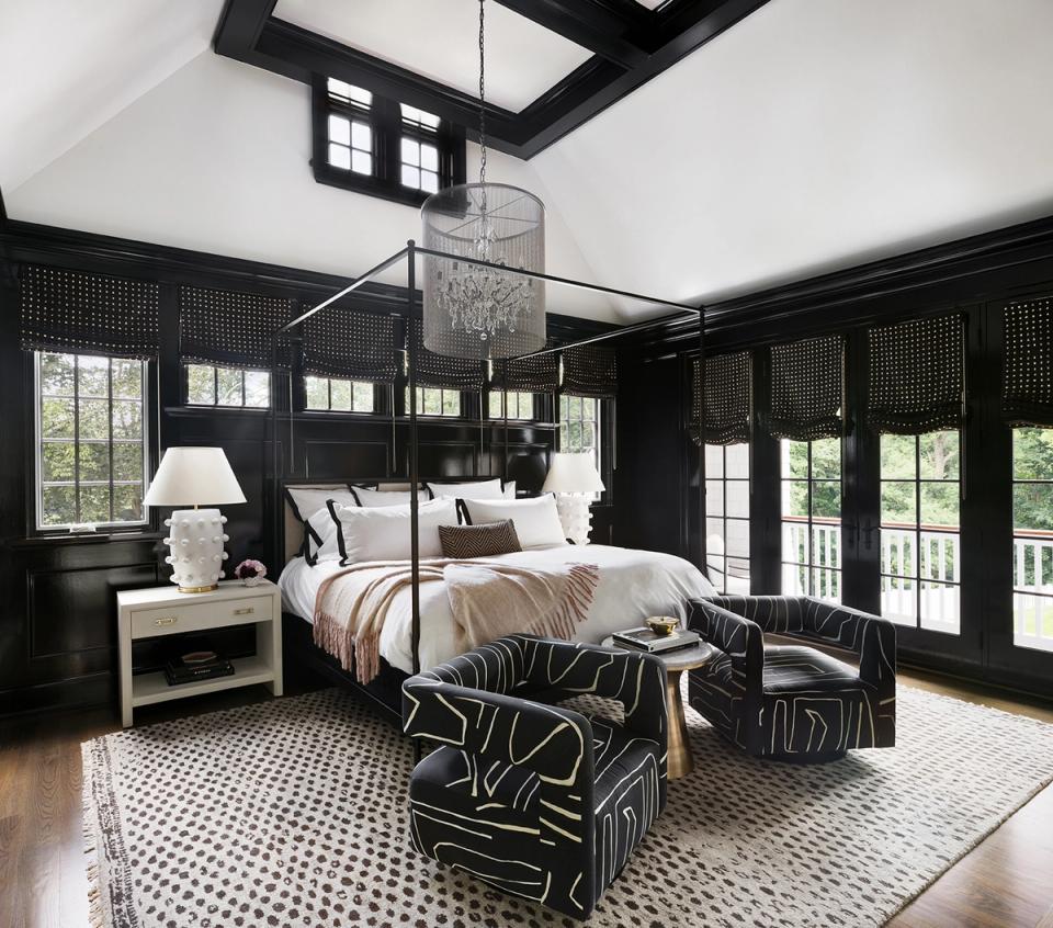 Luxe dark moody bedroom with black paneled walls, white bedding, and patterned accent pieces