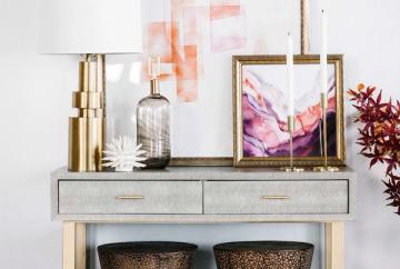 Contemporary console styling with brass elements, watercolor art, and woven baskets
