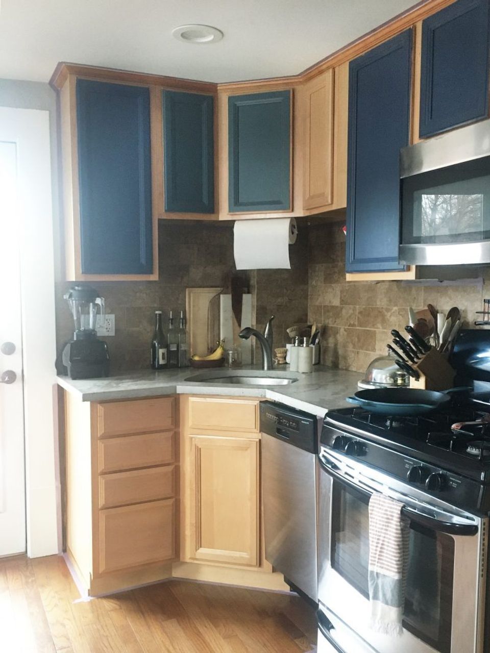 Transitional kitchen corner with navy upper cabinets, natural wood base, and dark subway tile backsplash