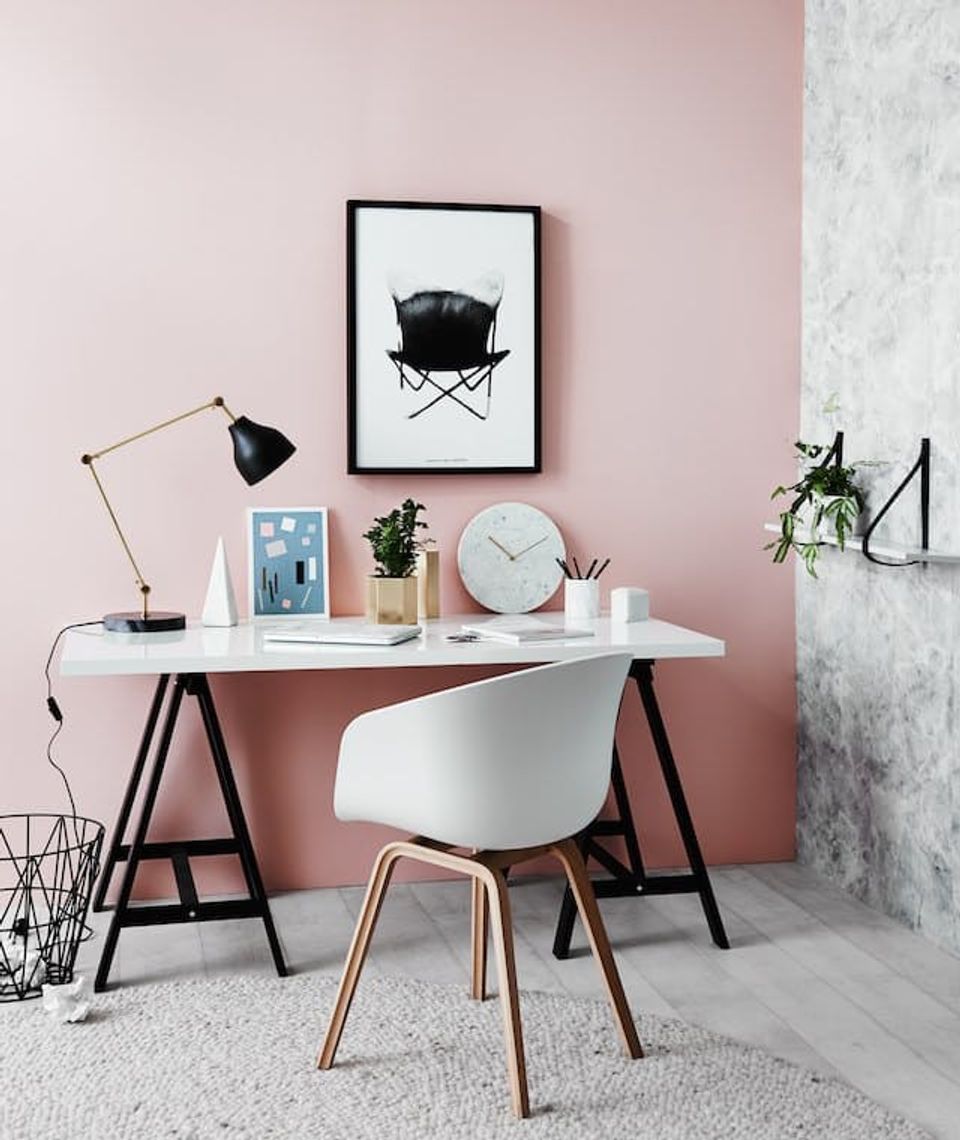 Minimalist workspace with dusty rose accent wall, mid-century desk, and Scandinavian styling