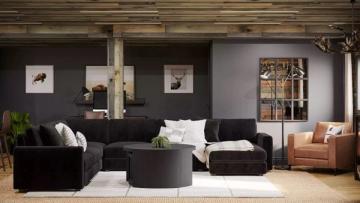 Modern living room with black accent wall, charcoal sectional, cognac leather chair, and warm wood tones creating an inviting industrial aesthetic.