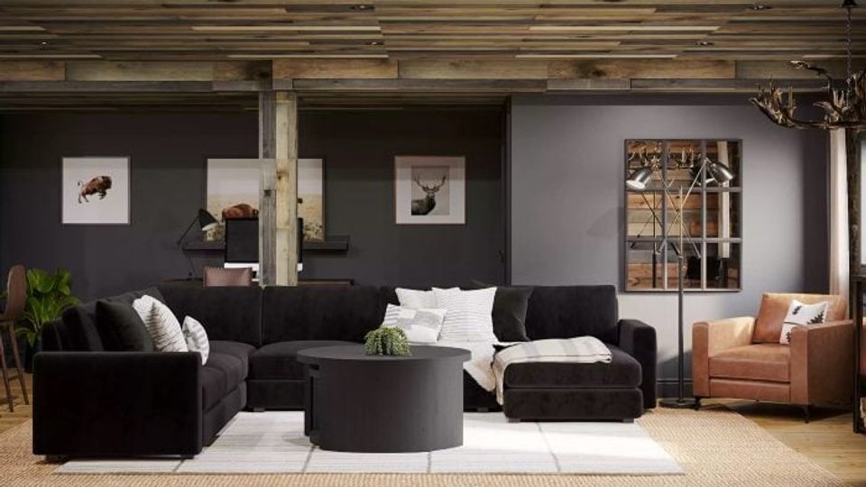 Modern living room with black accent wall, charcoal sectional, cognac leather chair, and warm wood tones creating an inviting industrial aesthetic.