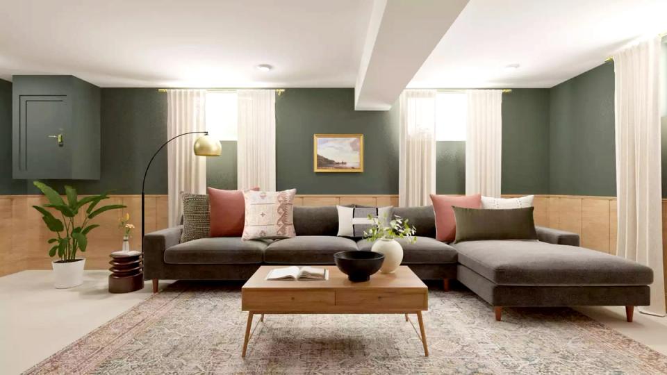 Mid-century modern lounge with sage green walls, dark sofa, warm wood legs, and coral accent pillows