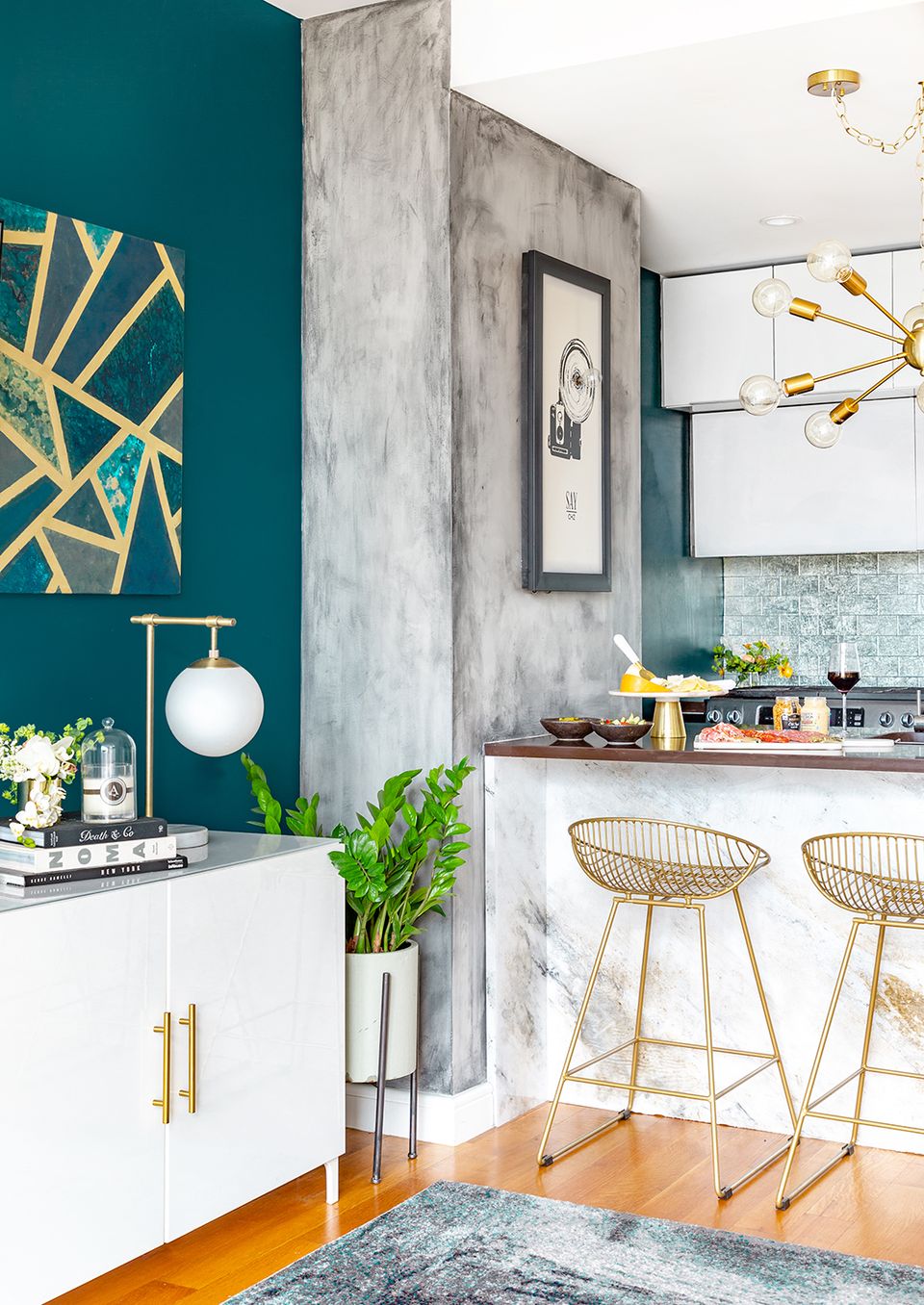 Modern kitchen with rich teal accent wall, concrete finishes, and brass geometric details
