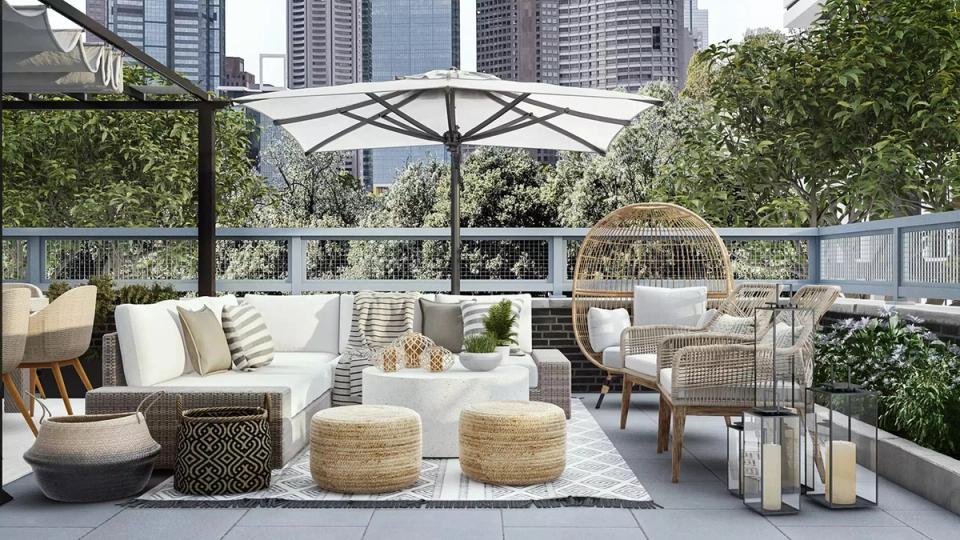Modern rooftop terrace with woven seating, white umbrella, and urban skyline views in warm, natural tones.