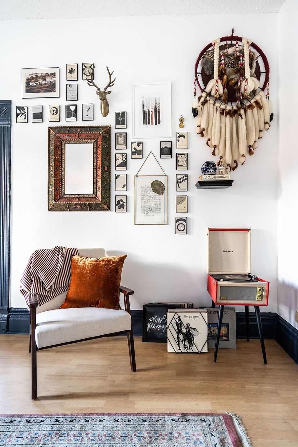 Eclectic boho living room featuring mixed-media gallery wall with natural textures, macramé, vintage frames, and warm leather accents
