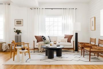 Scandinavian living room with cream sofa, wooden chairs, geometric rug, and neutral palette creating airy, cohesive space
