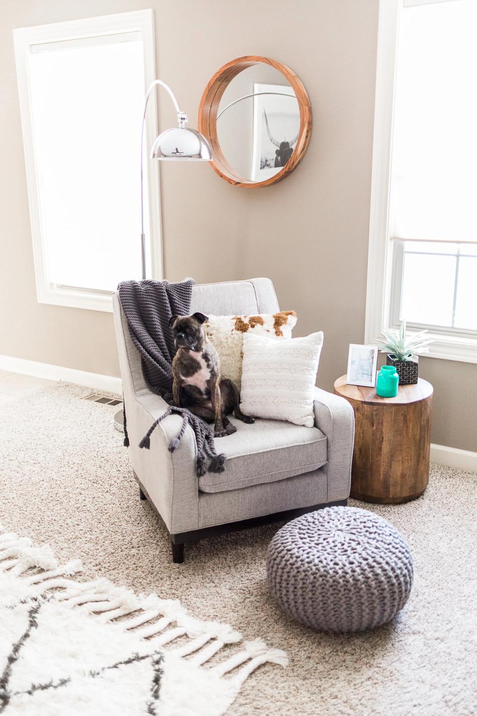 Warm, minimalist reading nook with neutral tones, copper mirror, and cozy woven accents