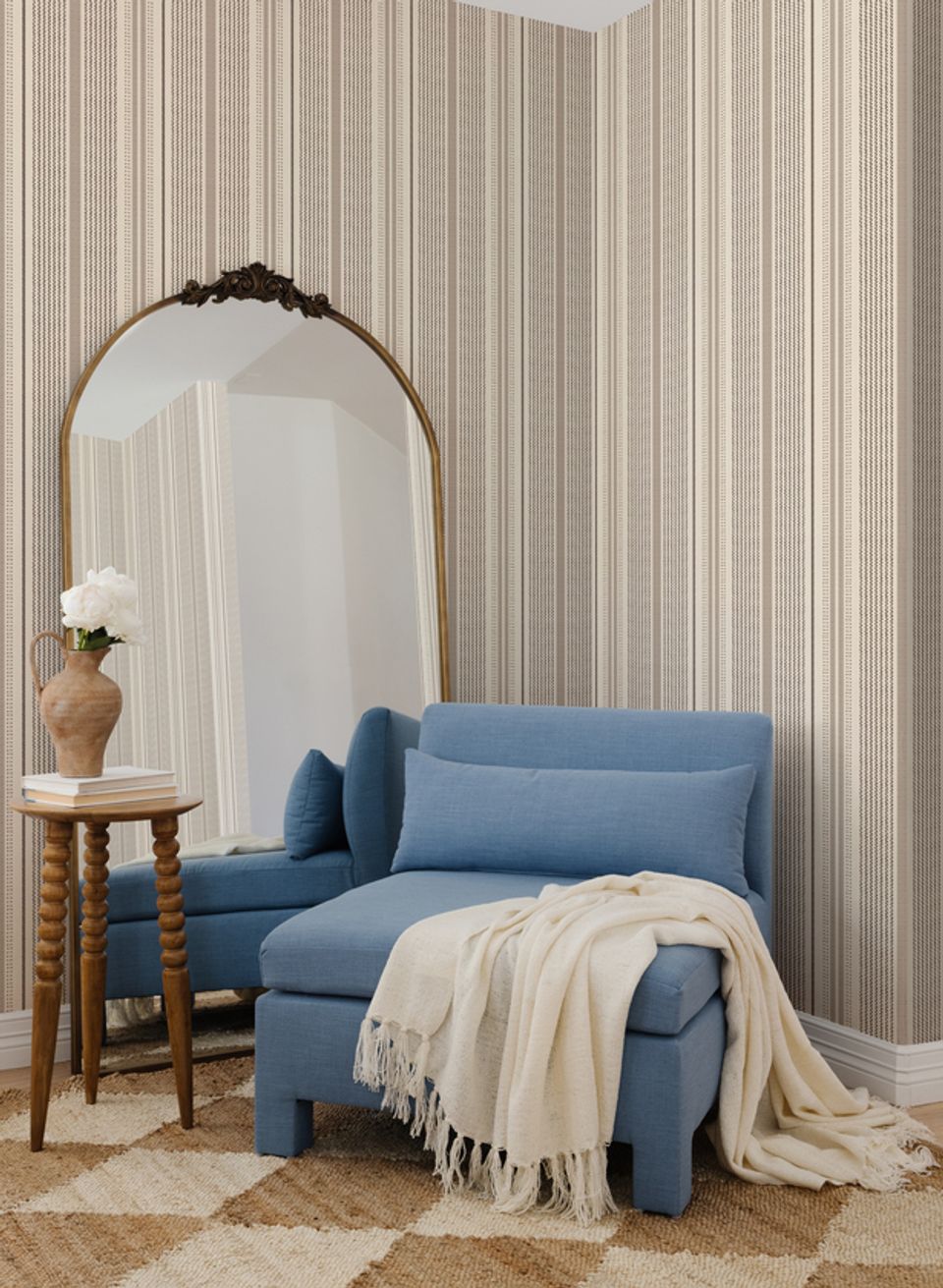 Minimalist bedroom with vertical striped wallpaper, slate-blue seating, and curved mirror creating restful, understated sophistication.