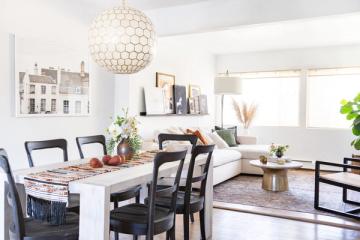 Bright modern dining space with white marble table, black chairs, and geometric pendant light