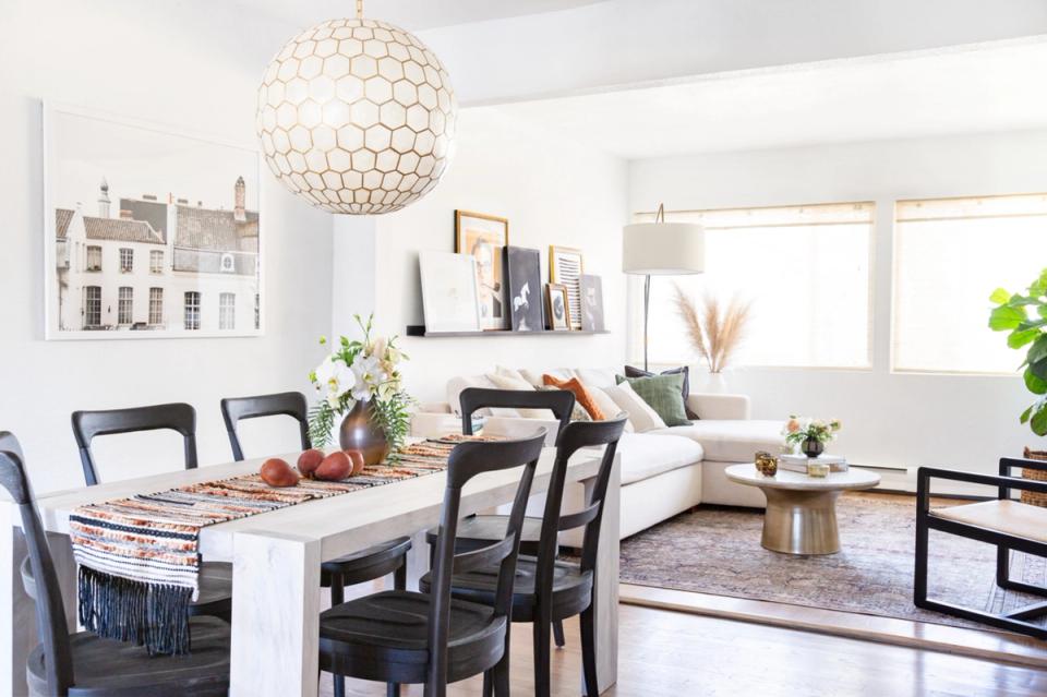 Bright modern dining space with white marble table, black chairs, and geometric pendant light