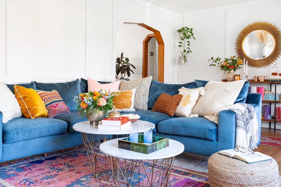Eclectic blue sectional sofa with bold patterned rug, colorful throw pillows, and curated vintage-inspired accessories creating vibrant, artsy living room