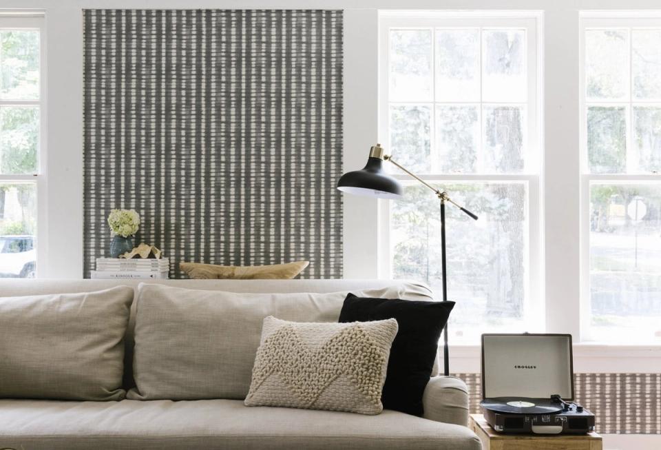 Modern minimalist living room with black arc floor lamp, neutral sofa, and geometric patterned accent wall