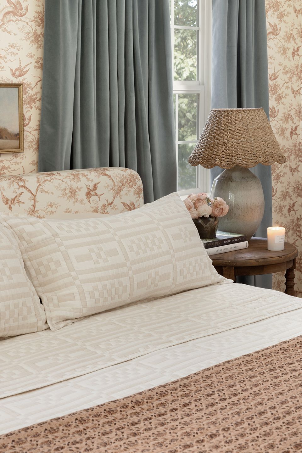 Traditional bedroom featuring floral toile wallpaper, sage curtains, and cream bedding with layered neutral textures.