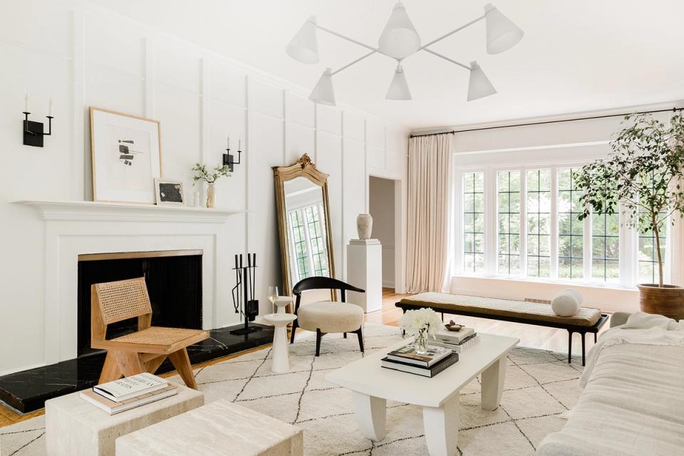 Modern minimalist living room in cream and white with geometric pendant, fireplace, and natural light