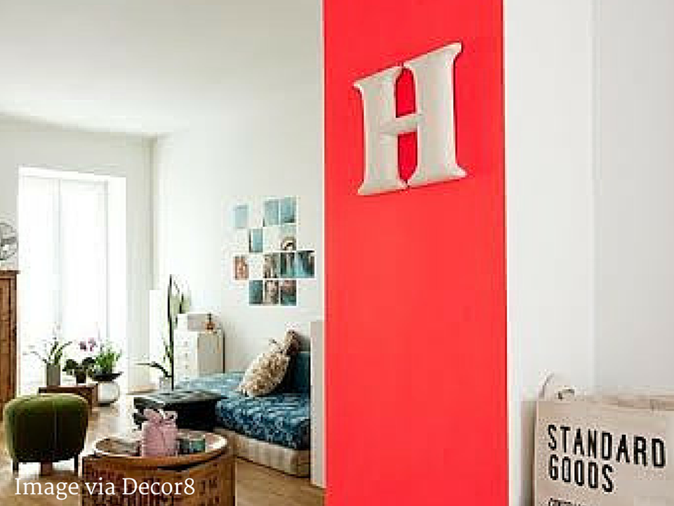 Bright red accent wall with oversized letter 'H' in scandinavian bedroom space