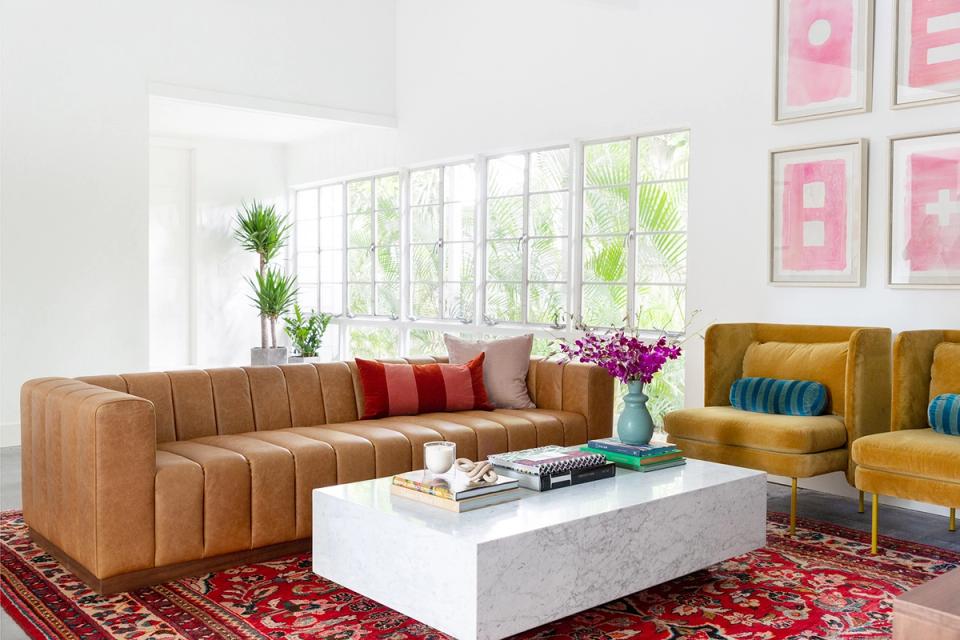 Contemporary space with tan leather sectional, red patterned rug, and vibrant pink gallery wall