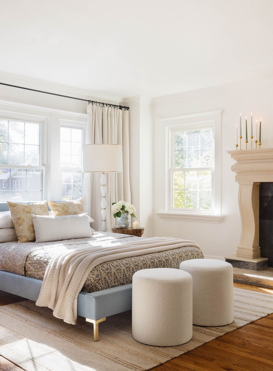 Serene bedroom with cream palette, fireplace, and minimalist furnishings near windows