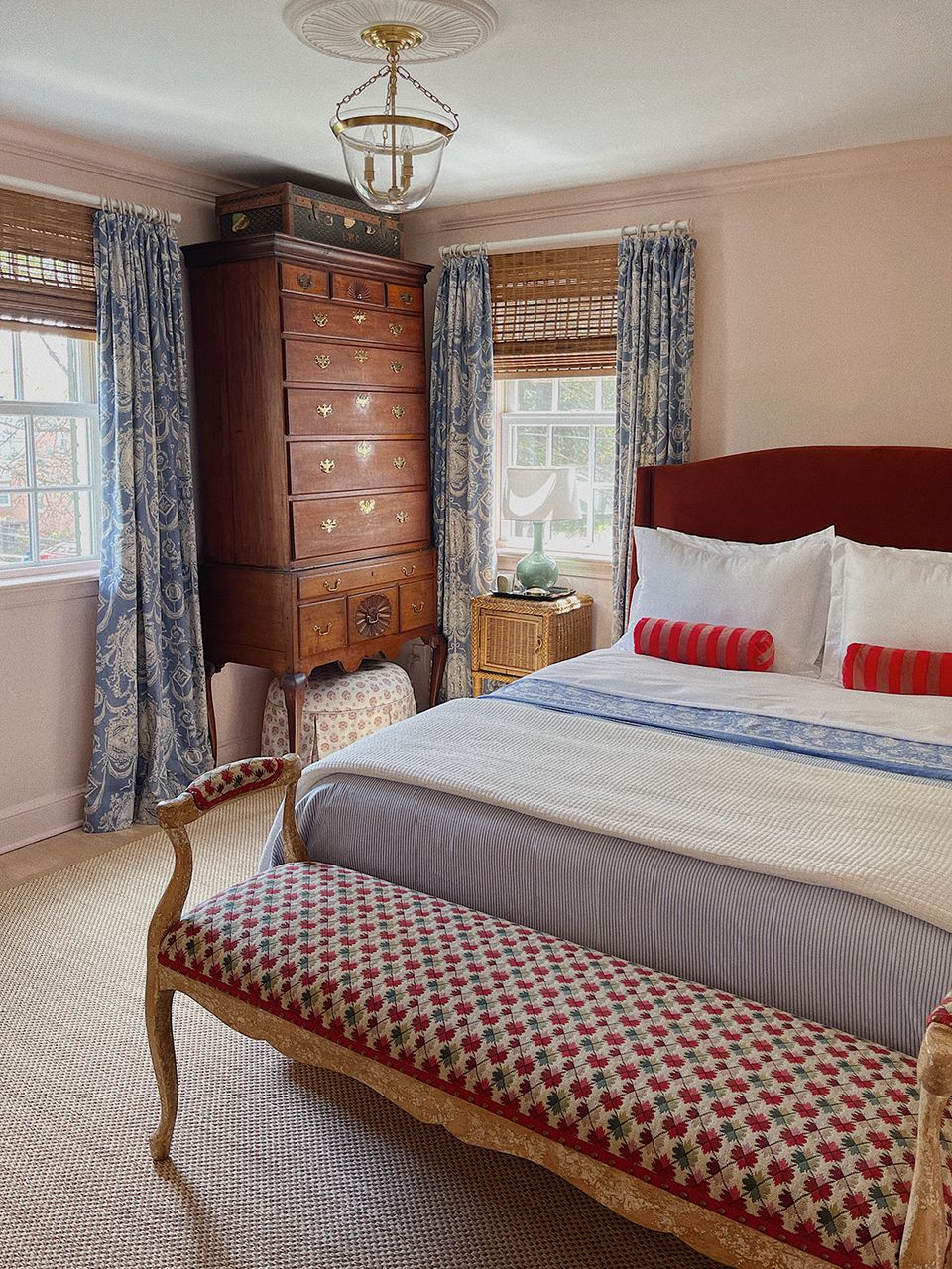 Traditional maximalist bedroom blending wood furniture, blue patterned curtains, and red accents
