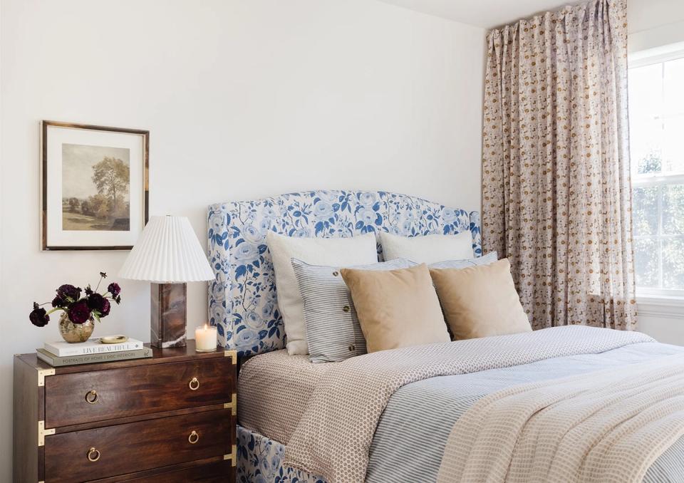 Serene traditional bedroom with blue floral headboard, neutral linens, and warm wood nightstands creating a classic romantic aesthetic