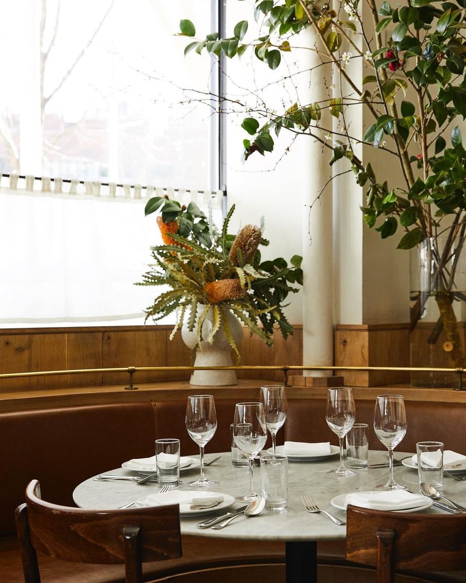 Contemporary dining space with wood paneling, greenery arrangement, and minimalist table setting