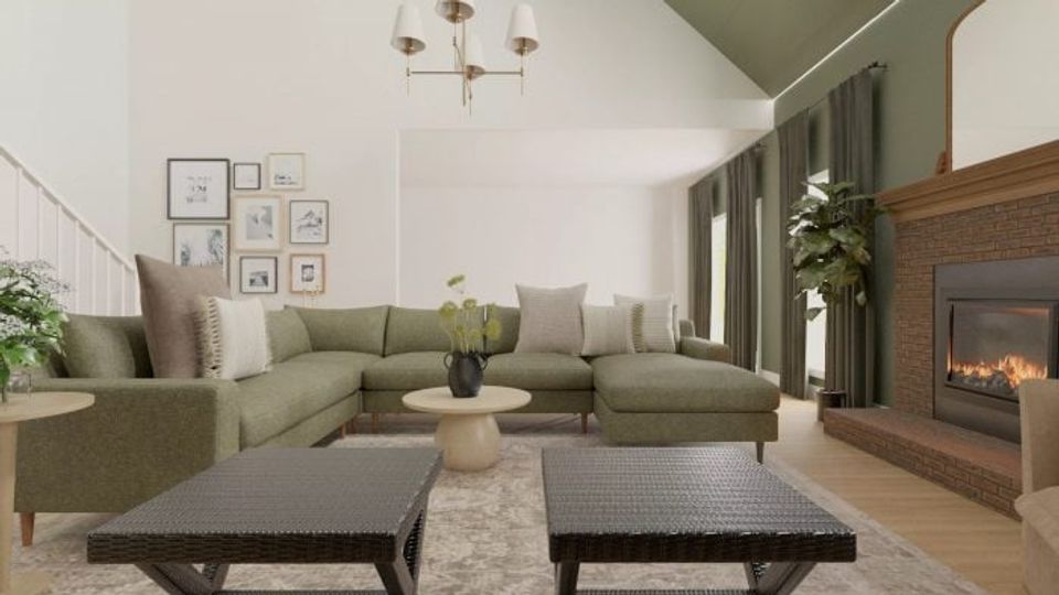 Warm modern living room with sage green sectional, wood-burning fireplace, dark coffee table, and earthy neutral palette