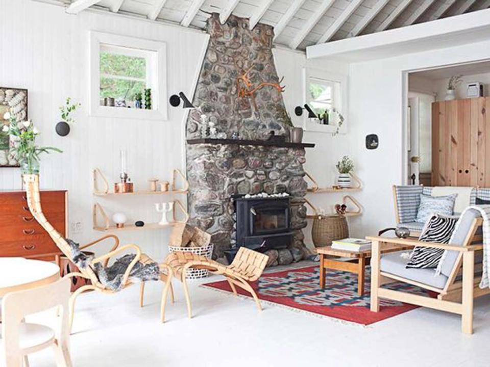 Rustic cabin living room with stone fireplace, natural wood beams, warm cream walls, and woven accents