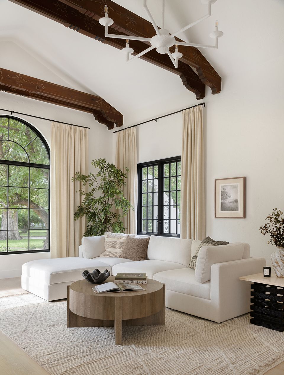 Modern minimalist space with cream seating, dark wood beams, and natural greenery