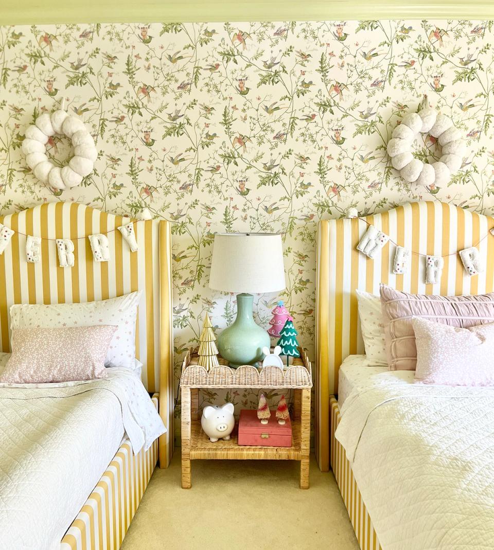 Bright maximalist twin bedroom with yellow striped headboards, floral wallpaper, and cheerful pastels