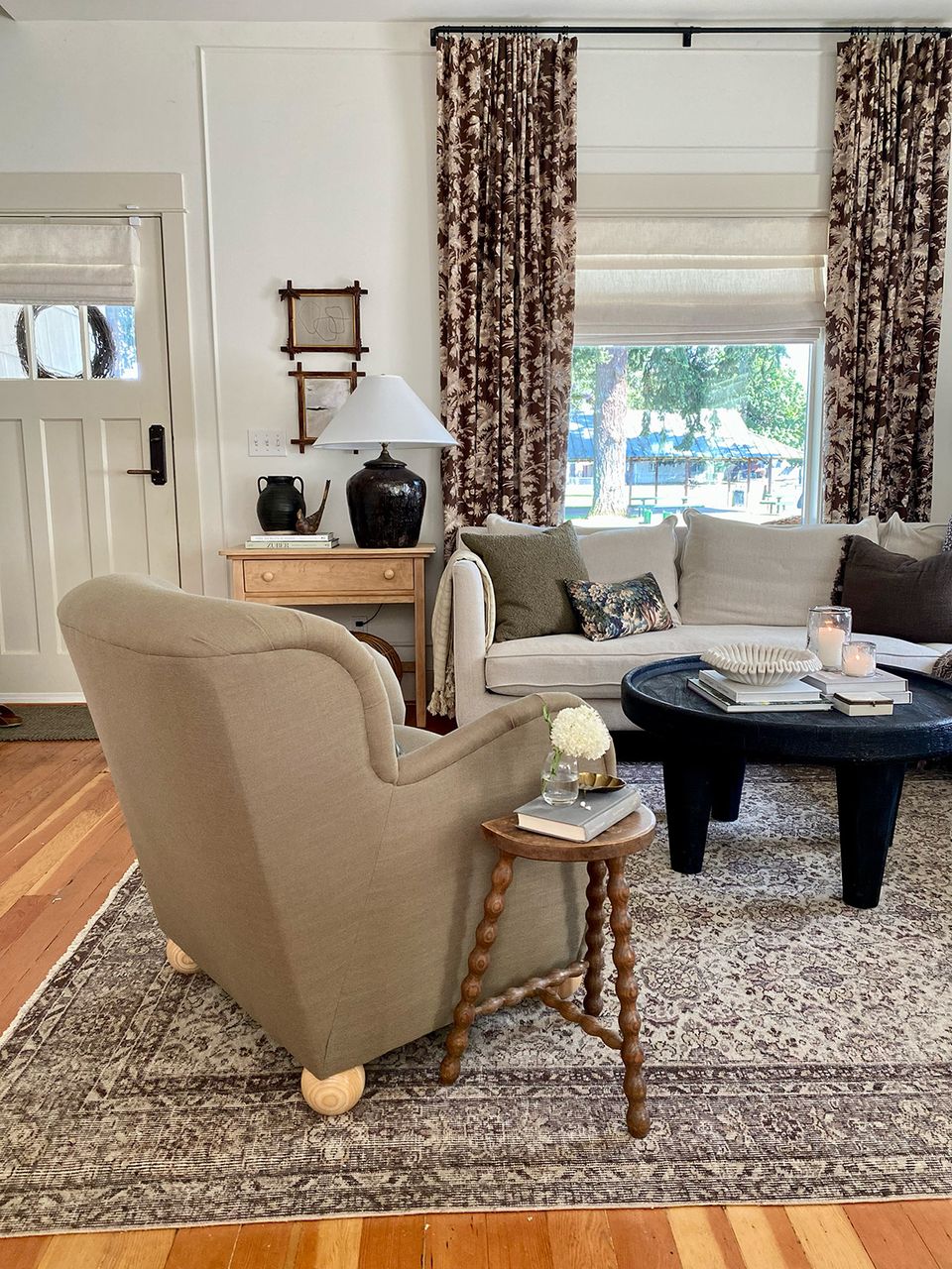 Elegant traditional living room with rolled-arm chair, patterned curtains, and timeless neutral tones