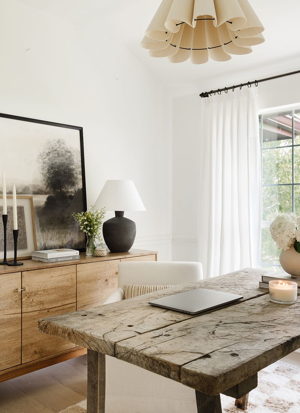 Modern rustic workspace with raw wood desk, sculptural pendant light, and serene neutral tone backdrop