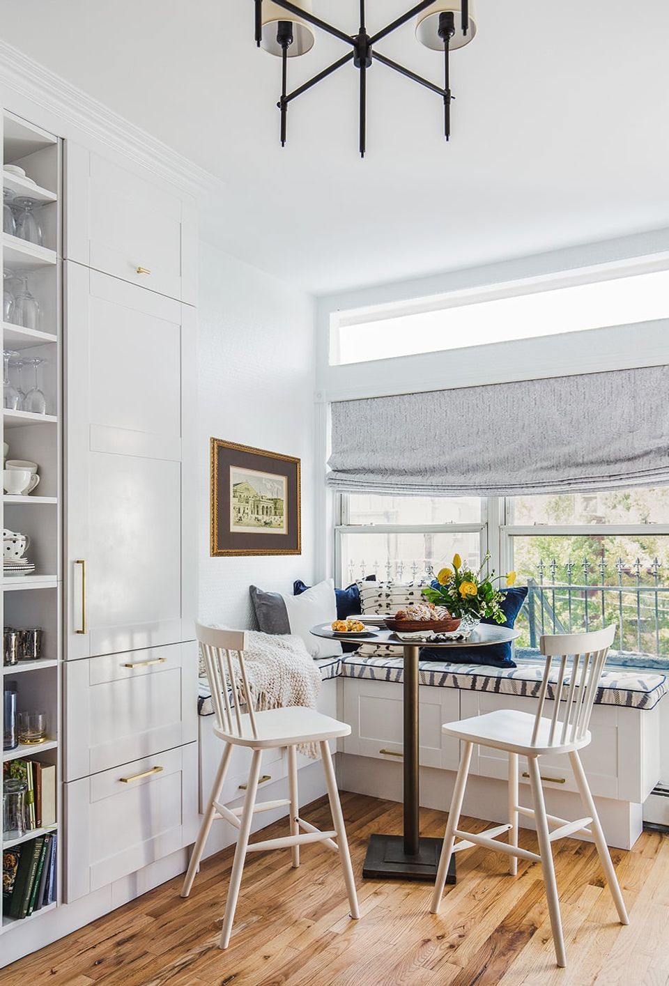 Coastal farmhouse dining room with white built-ins, light wood bar stools, modern black pendant, and serene window views