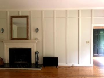 Classical living room with cream paneled walls, fireplace mantel, warm wood flooring, and elegant symmetrical design