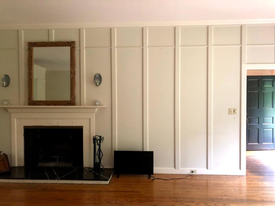 Classical living room with cream paneled walls, fireplace mantel, warm wood flooring, and elegant symmetrical design