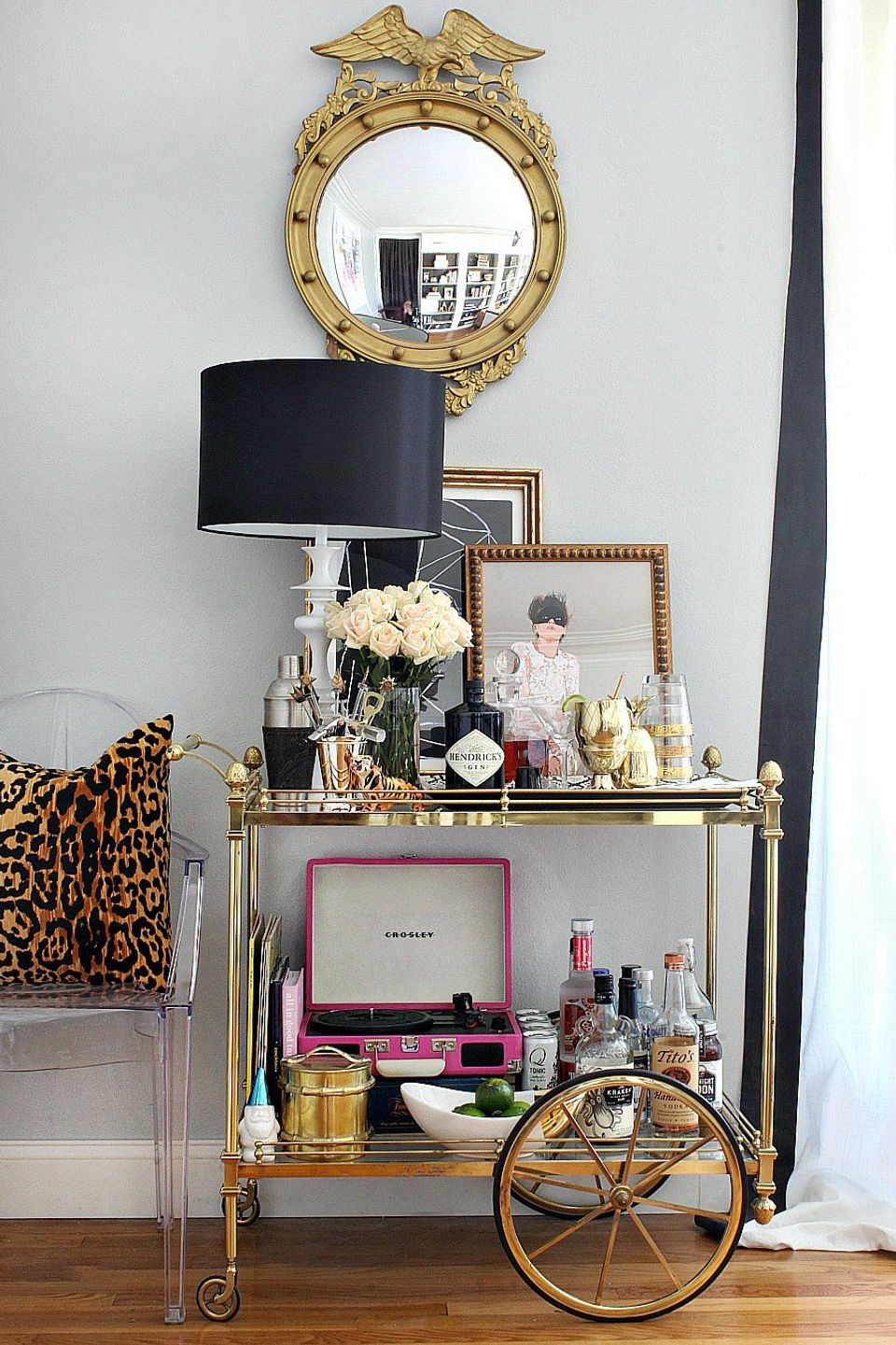 Glam gold bar cart with black lamp, ornate mirror, leopard print, and brass accents