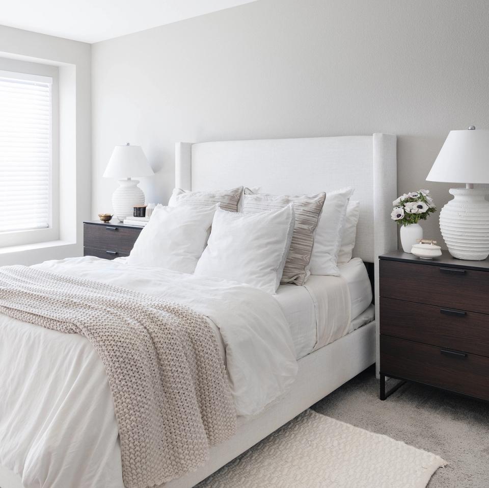 Serene minimalist bedroom in cream and white with upholstered headboard and dark wood nightstands