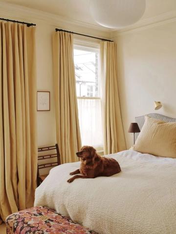 Serene bedroom blending English cottage warmth with 1970s retro charm through soft butter tones, golden curtains, and vintage-inspired accents