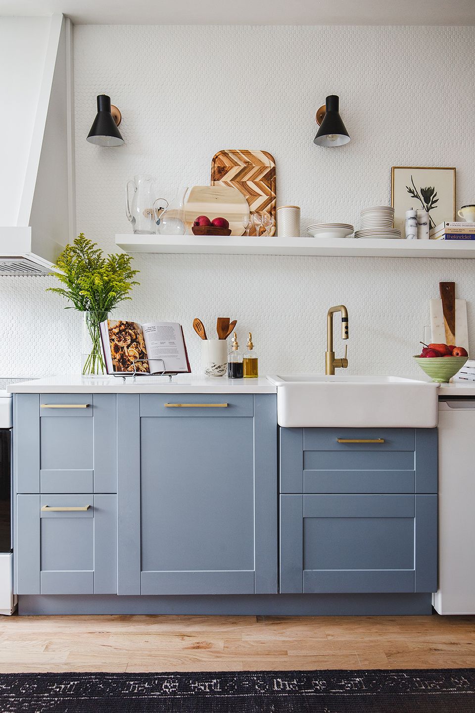 Modern farmhouse kitchen with soft blue lower cabinetry, open shelving, white subway tile, and brass hardware