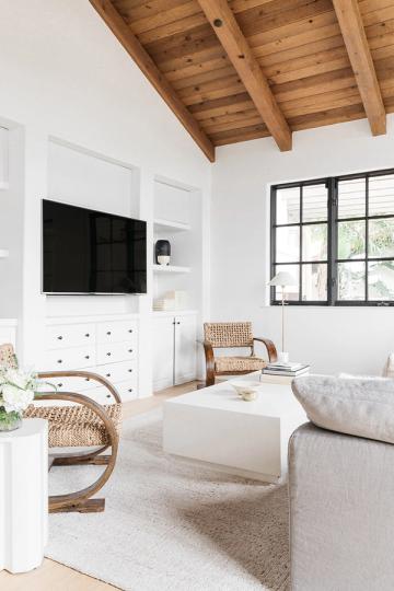 Bright farmhouse bedroom with white TV cabinet, exposed wood ceiling, and natural textures