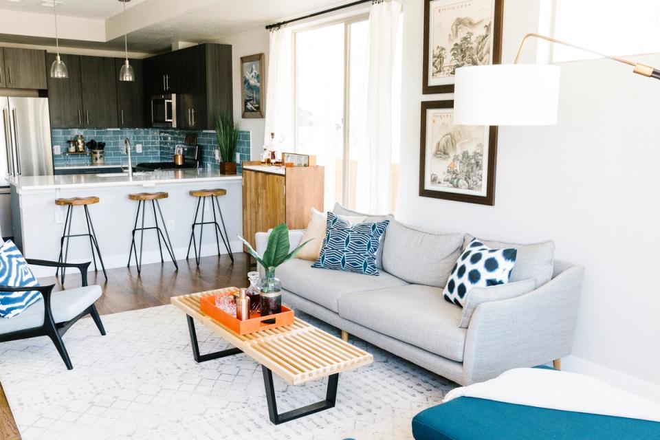 Scandinavian hygge living room with warm wood accents, soft gray sofa, and blue geometric pillows creating cozy, inviting atmosphere.