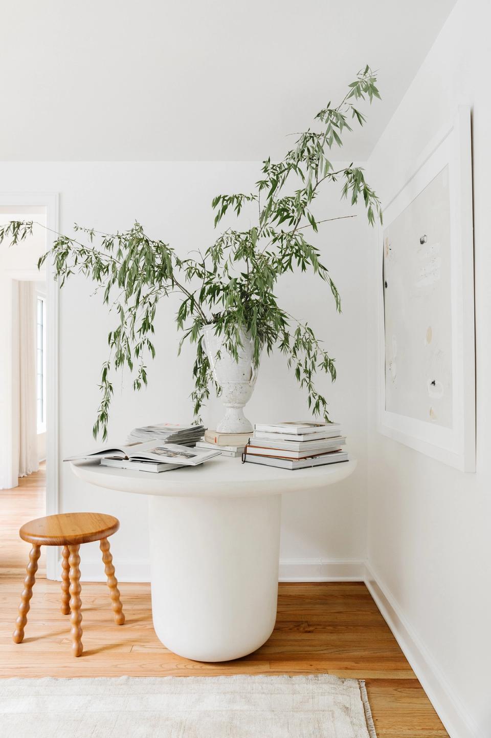 Minimalist stairwell nook with cascading greenery in white planter, stacked books, and natural wood accents in calm, clean aesthetic.